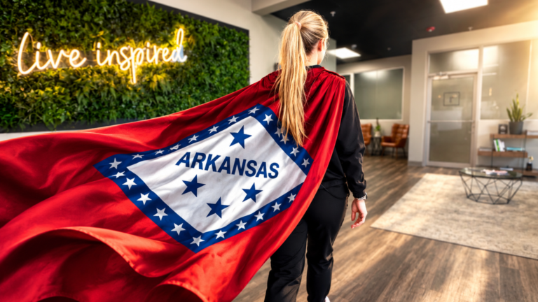 Team member walking confidently with the Arkansas state flag flowing behind her like a cape, symbolizing pride in serving Northwest Arkansas.